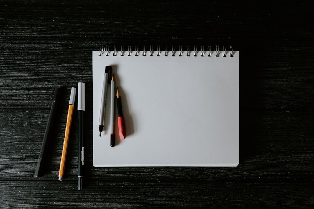 Notebook calendar and pen on a wooden table with autumn leaves